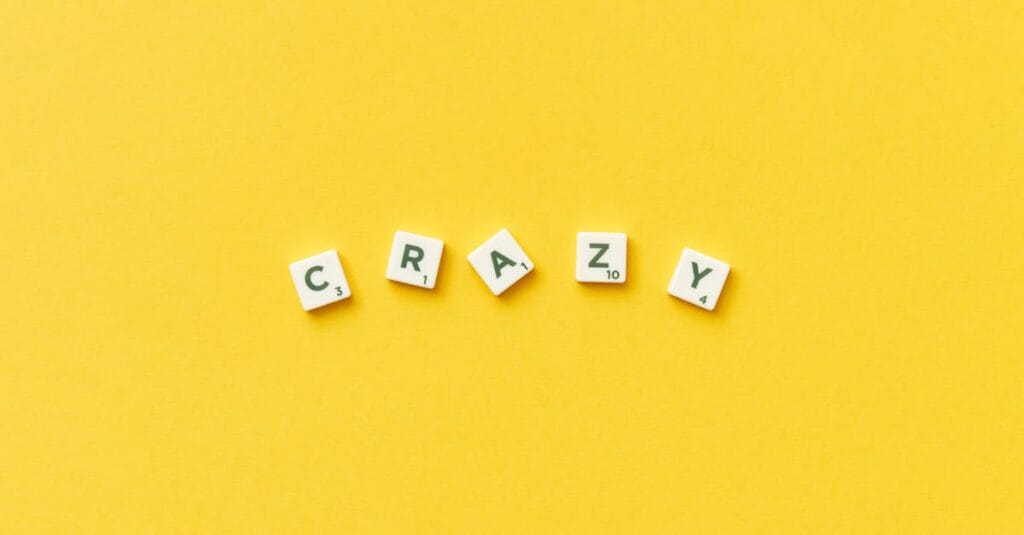 Scrabble tiles spelling 'crazy' on a vibrant yellow background.