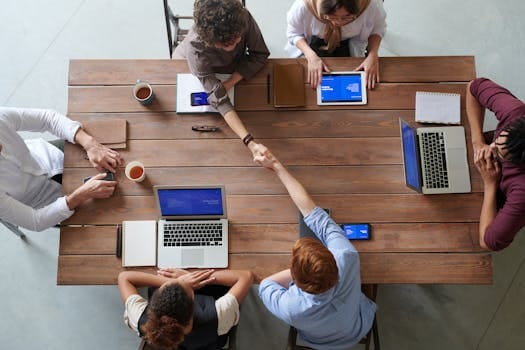 Overhead view of colleagues in a work meeting using laptops and tablets, emphasizing teamwork and technology. pic by fauxels via pexels